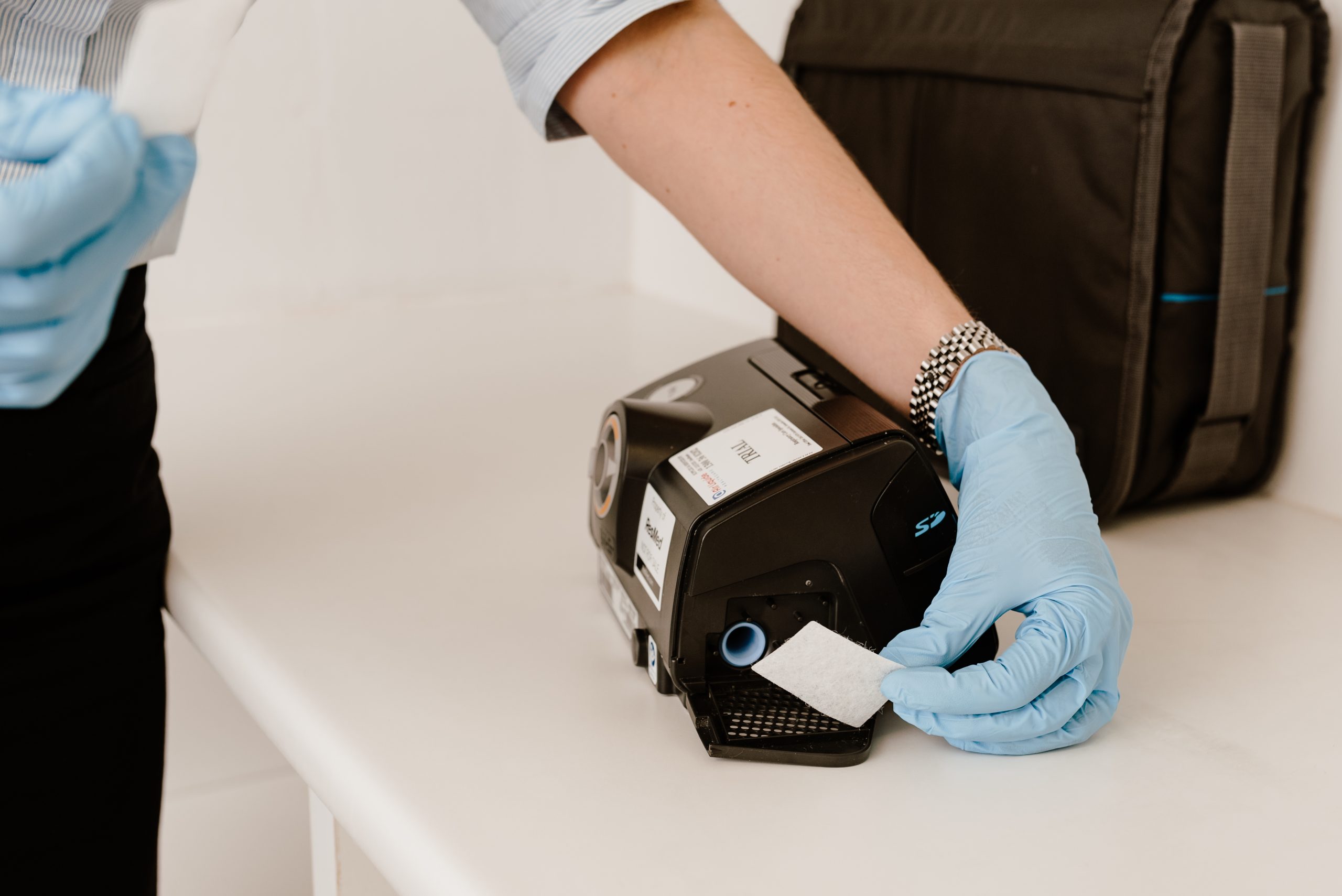 A white air filter pad being lifted out of the open filter slot of a PAP device