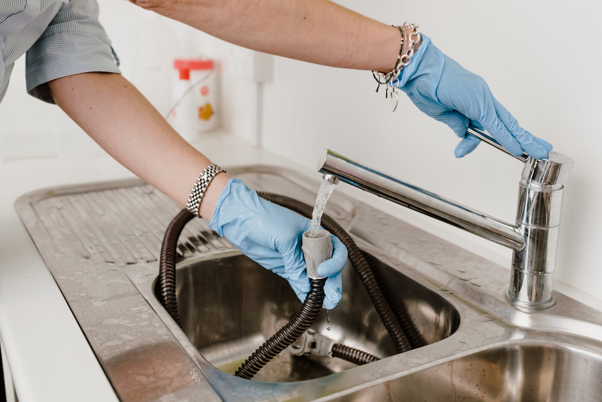 Gloved hands running clean water from the tap through the air tubing in a sink