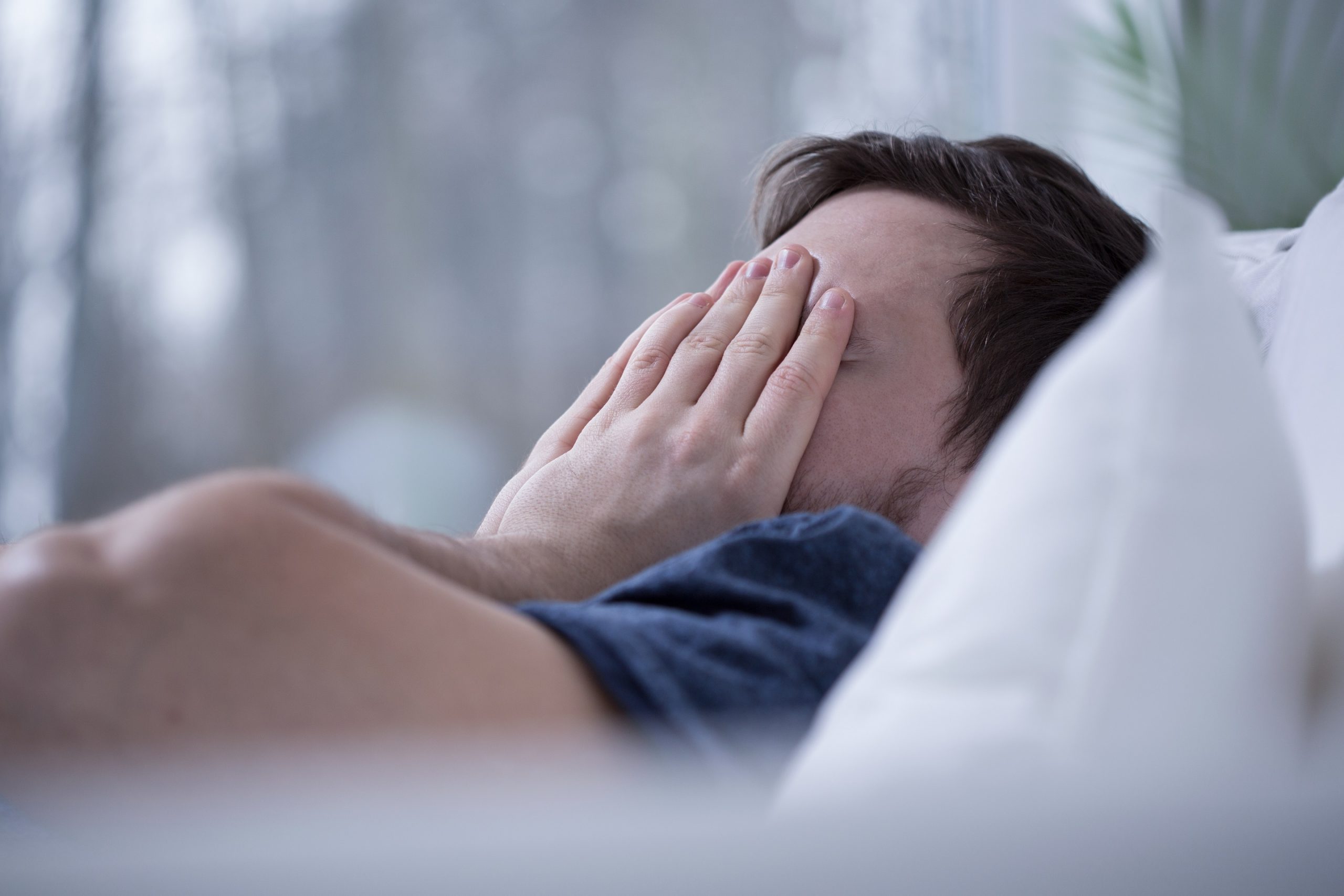 A man lying awake in bed at night, eyes open