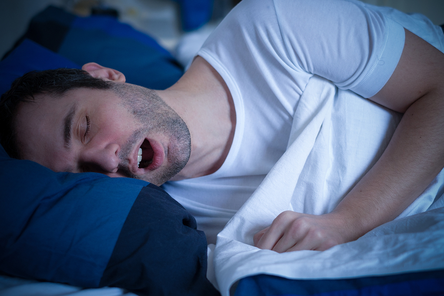 A couple asleep in bed, one of them wearing a PAP mask