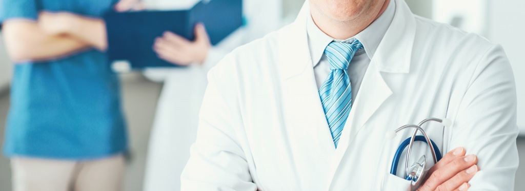 A sleep physician in a white coat, arms folded, with colleagues behind